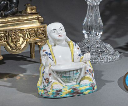 null Bouddha assis en porcelaine, tenant entre ses jambes une demi-sphère du globe...