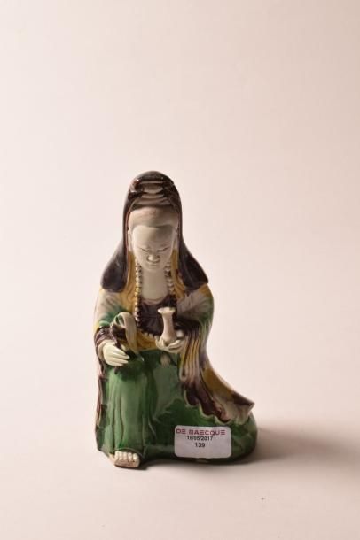 CHINE Kuan-hin à décor arlequin assise tenant un vase et un feuillage XVIIIe siècle,...