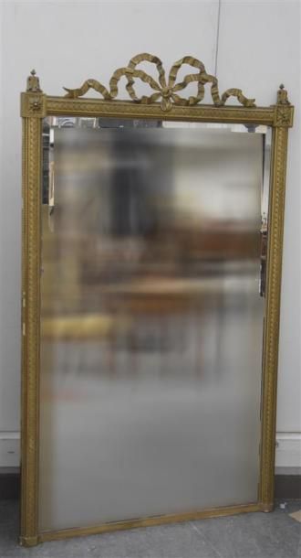 MOBILIER Miroir en stuc doré à frises de piastres et de perles, le fronton orné d'un...