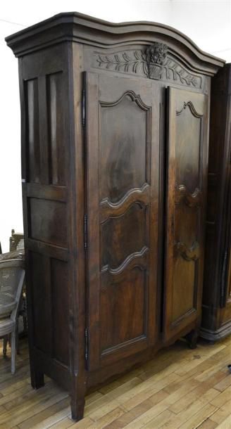 MOBILIER Armoire en noyer à fronton cintré, deux portes à panneaux chantournés, le...