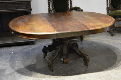 MOBILIER Table ronde à allonges centrales en chêne sculpté, à fût quadripode sculpté...
