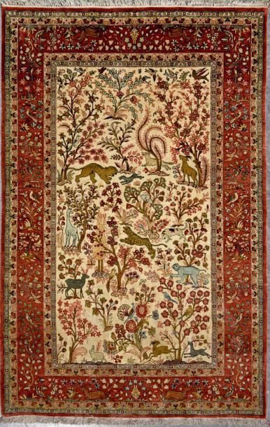 ISPAHAN Beau tapis en soie, champ beige à décor de chasse dans des rinceaux; la bordure...