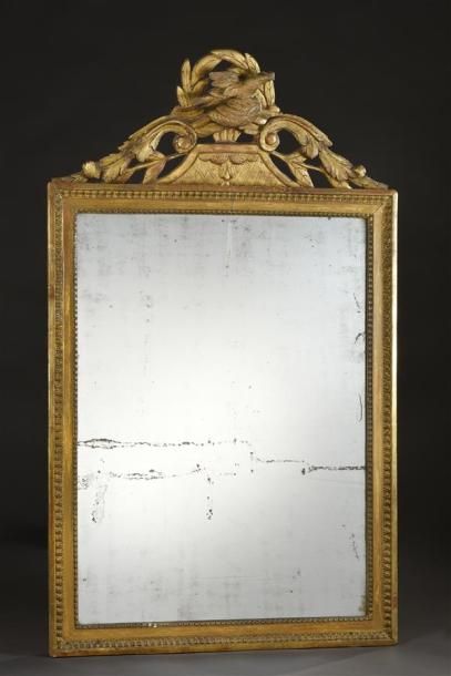 MOBILIER Miroir en bois sculpté et doré à décor de frise de perles et feuilles d'eau...