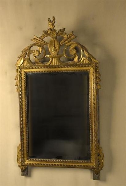 MOBILIER Miroir en bois sculpté et doré à moulures de perles et rubans tors. Le fronton,...