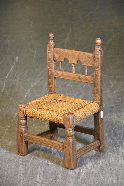 null Chaise d'enfant en bois incisé de motifs géométriques, assise paillée H. 59...