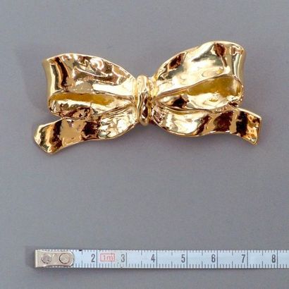 null YVES SAINT LAURENT. Broche figurant un noeud en métal doré bosselé. Signé. Bon...