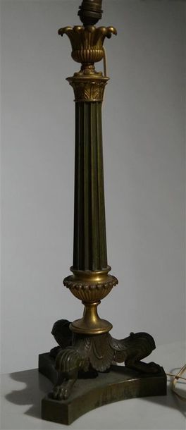 null Une lampe en bronze patiné et doré, le fût cannelé à chapiteau corinthien reposant...