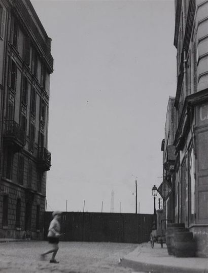 Roger Parry (1905-1977) Petit garçon traversant une rue de Paris sur fond de Tour...