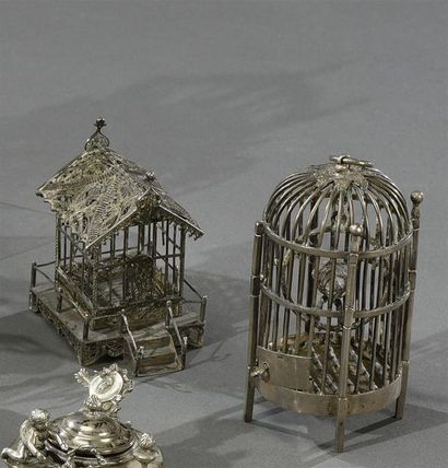  Deux cages miniatures, l'une ronde renfermant un perroquet sur un portant et une...