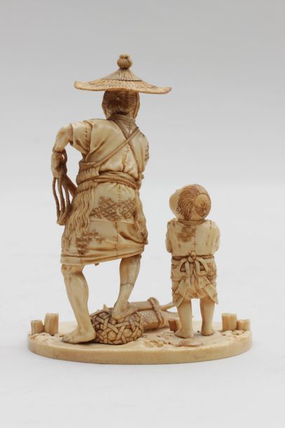 null OKIMONO en ivoire représentant un pêcheur tenant un filet, un enfant lui présentant...