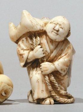 JAPON NETSUKE en ivoire représentant un homme supportant le masque du renard Kitsune....