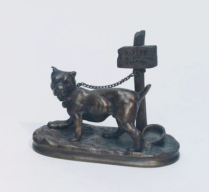 null bronze print with patina representing a guard dog tied to a post where it is...