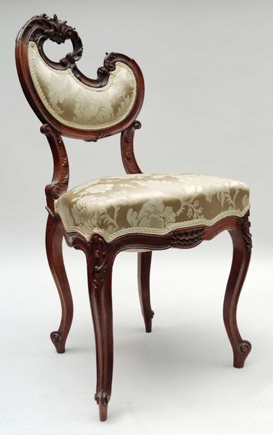 null Pair of chairs in carved walnut, the back of contoured form with floral decoration,...