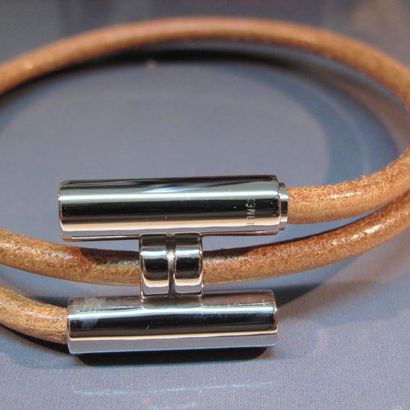 HERMES Bracelet enroulé formé d'un lien en cuir fermé par un H en métal argenté....