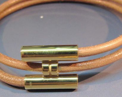 HERMES Bracelet enroulé formé d'un lien en cuir fermé par un H en métal doré. Signé....