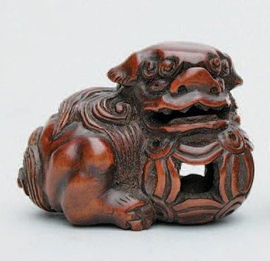 null NETSUKE en bois représentant un shishi, les pattes posées sur une balle. Japon,...