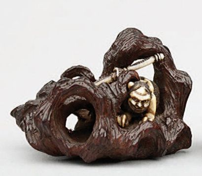 null NETSUKE en bois et ivoire représentant un oni se dissimulant dans des rochers,...