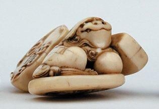 null NETSUKE en ivoire formant cachet représentant un shishi tenant la perle sacrée...