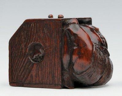 null NETSUKE en bois représentant un personnage assis, la tête dans une caisse en...