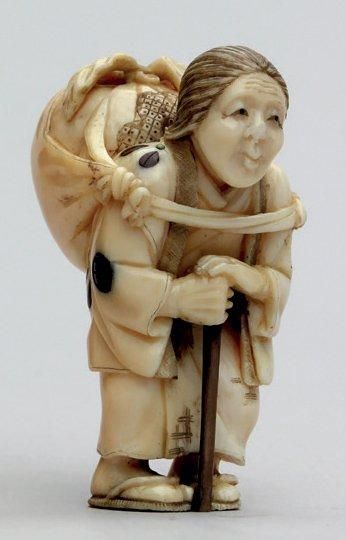 null NETSUKE en ivoire représentant une vieille femme appuyée sur sa canne, portant...
