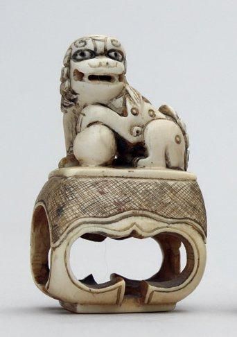 null NETSUKE en ivoire représentant un shishi sur un piédestal, la patte avant gauche...