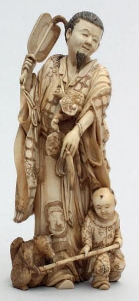 null OKIMONO en ivoire représentant un seigneur debout tenant un uchiwa, accompagné...