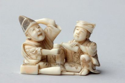 null NETSUKE en ivoire représentant une femme versant du saké à un homme, signé Koïshi.
Japon,...
