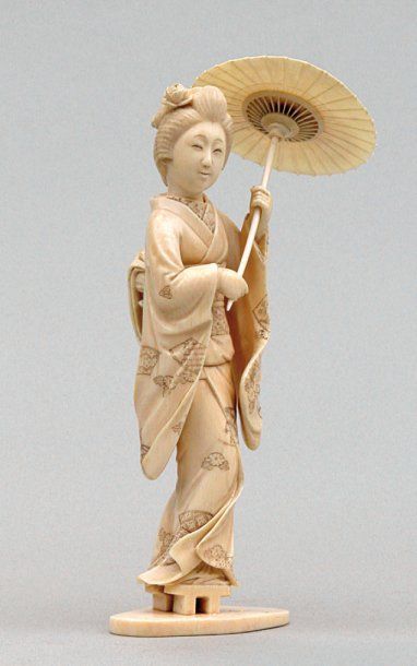 null OKIMONO en ivoire représentant une geisha debout, portant une ombrelle. Signé...