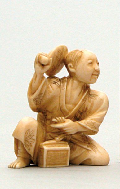 null OKIMONO en ivoire représentant un homme assis tenant d'une main un chasse-mouches...