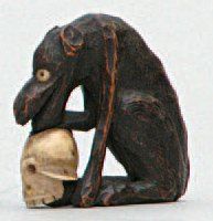  NETSUKE en bois et ivoire représentant un loup, un crâne entre ses pattes. Japon,...