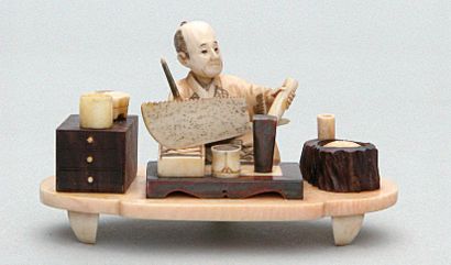 null OKIMONO en bois et ivoire représentant un artisan affutant une scie. Signé....