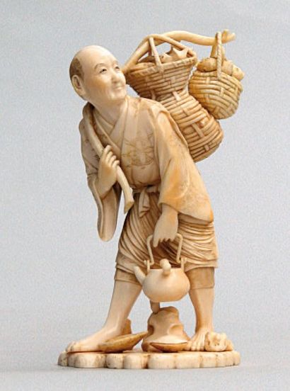  OKIMONO en ivoire représentant un pêcheur portant sur son dos deux corbeilles de...