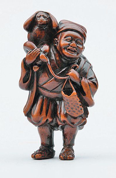 null NETSUKE en bois représentant un Sarumawashi, son singe sur l'épaule. Signé Gessho,...