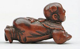 null NETSUKE en bois représentant un enfant couché sur le ventre et tenant un tambour....