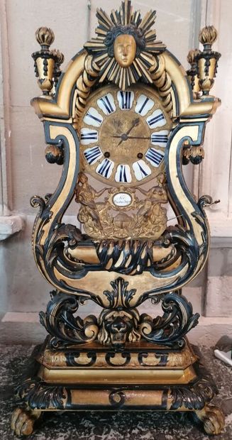 null Carved clock in blackened and gilded wood, it rests on a lion's head and is...