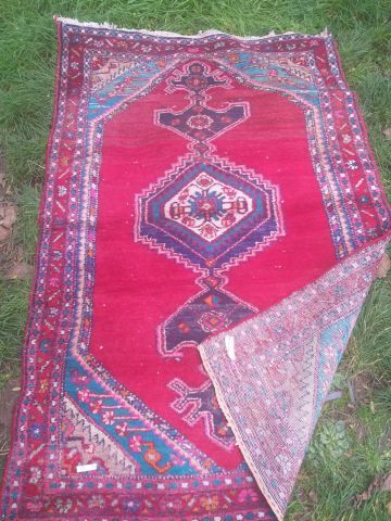 null Persian woollen rug with geometric and stylised plant motifs on a red background....