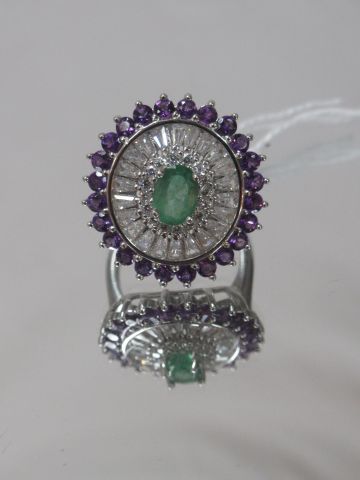 Silver ring, centered on an emerald, in a...