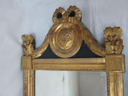  Wooden mirror and gilded stucco surmounted by a medallion topped by an enrubane,...