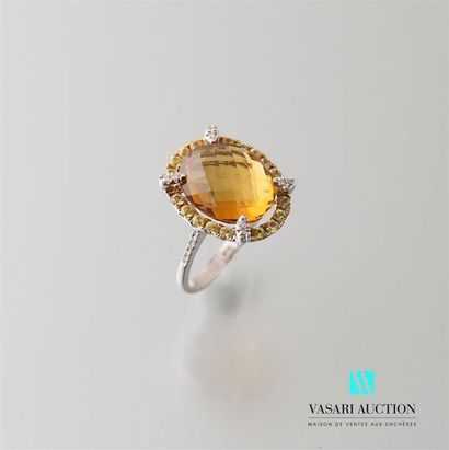 null White gold ring adorned in its center with a facetted oval citrine calibrating...