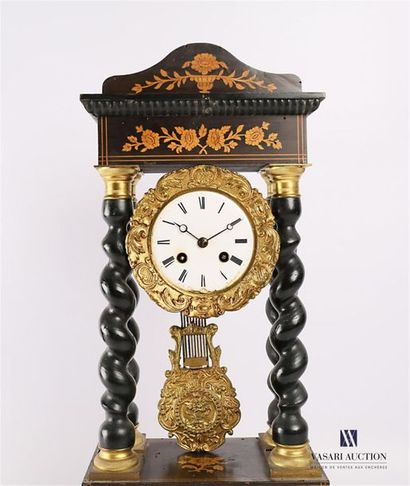 null A blackened wooden clock, the round enamelled dial is adorned with an acanthus...