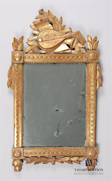 null A moulded, gilded and carved wooden mirror, it is surmounted by a pediment decorated...