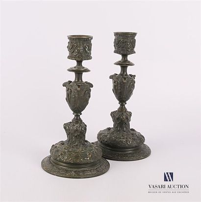 null Pair of bronze candleholders with a green patina resting on a pedestal with...