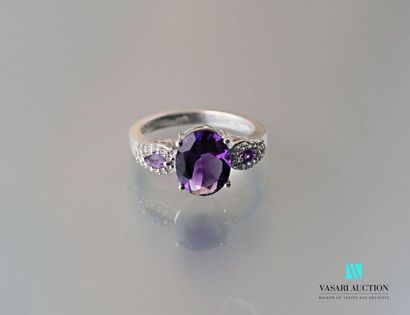 null Silver ring centered on an oval amethyst shouldered by two shuttle amethysts...