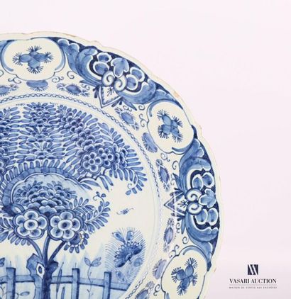 null DELFT
Round earthenware dish decorated with a flowering tree in front of a fence...