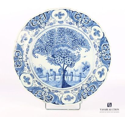 null DELFT
Round earthenware dish decorated with a flowering tree in front of a fence...