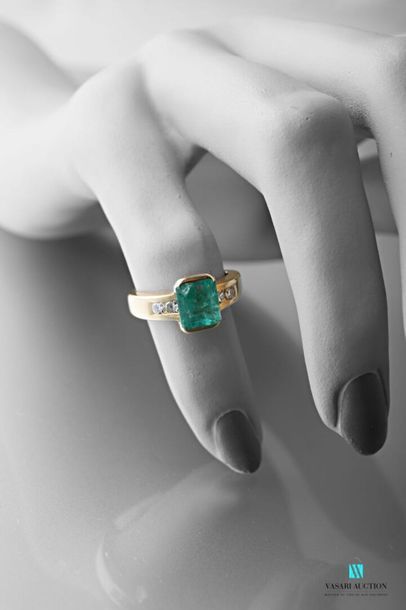 null 750 thousandths yellow gold ring set with a rectangular emerald shouldered with...