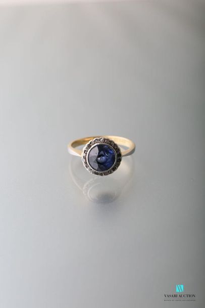 null 750 thousandths gold ring set with a central round synthetic sapphire surrounded...