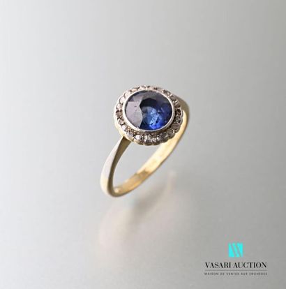 null 750 thousandths gold ring set with a central round synthetic sapphire surrounded...