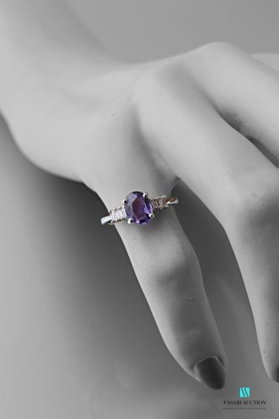 null 750 thousandths white gold ring centered on an oval-shaped lilac sapphire calibrating...