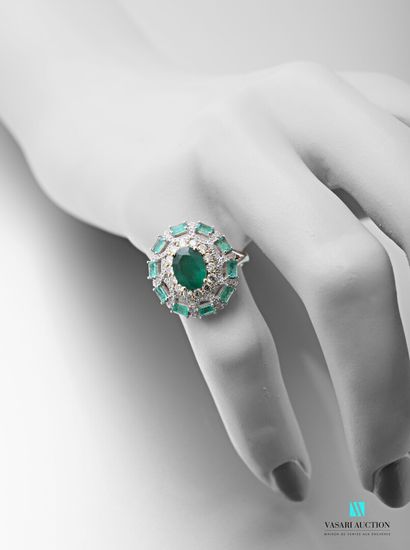 null 750 thousandths white gold ring adorned in its centre with an oval-cut emerald...